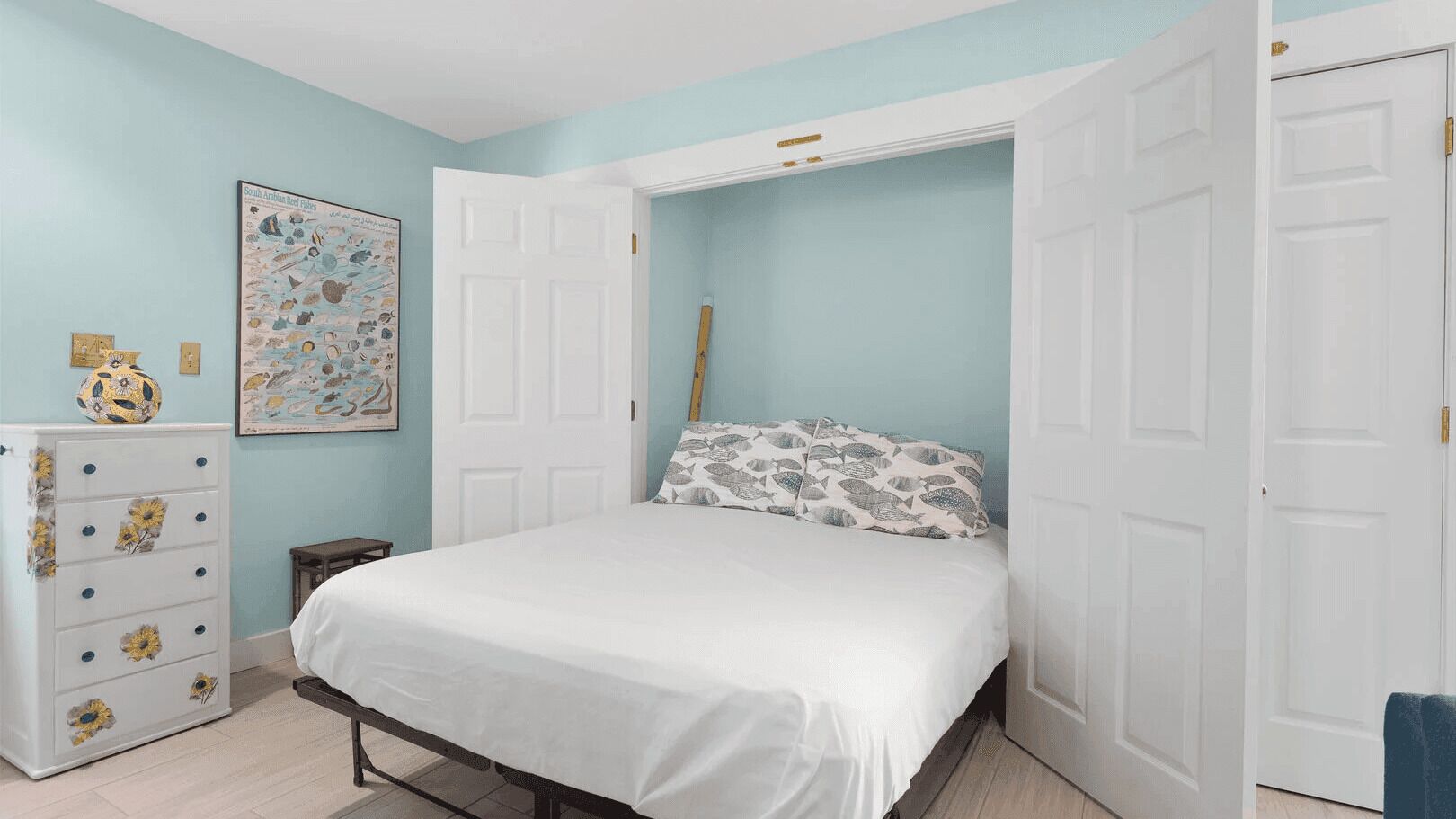 Une chambre à coucher avec un lit, une commode et un tableau accroché au mur.