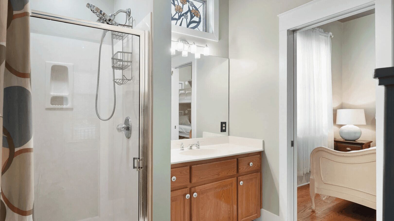 A bathroom with a shower, a sink, wooden cabinets, and a mirror.