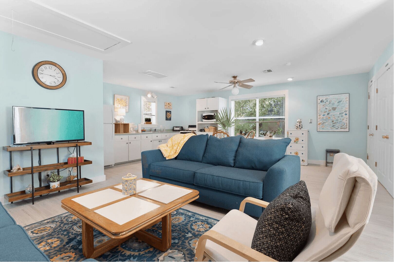 A modern living room with a blue sofa, wooden coffee table, and a TV on a stand.