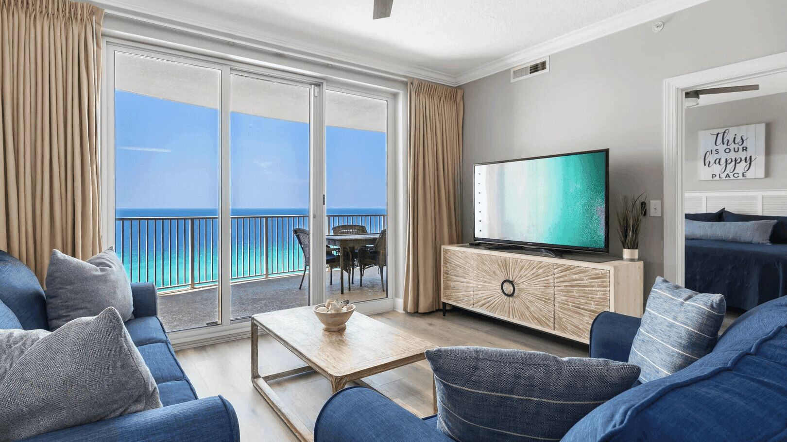 Un soggiorno moderno con una grande TV, un divano, un tavolino da caffè e vista sull'oceano.