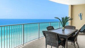 Un balcon avec vue sur l’océan, des meubles en osier et une bouteille de whisky écossais.