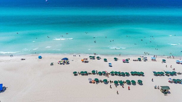 Une plage avec de nombreux parasols et beaucoup de monde.
