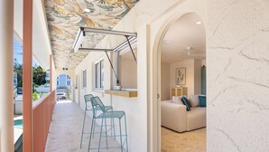 A modern interior with a kitchen area, bar seating, and a living room with a sofa and a painting. - The Shores Miami (Miami)