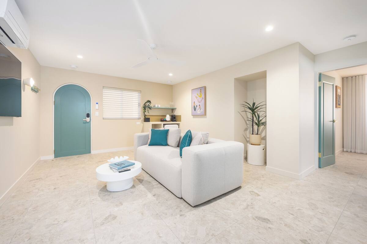 Un salon moderne avec un canapé blanc, une table basse et une porte de couleur turquoise.