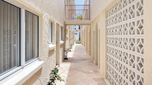 A narrow corridor with a tiled floor, a balcony with a railing, and a decorative wall with a geometric pattern. - The Shores Miami (Miami)