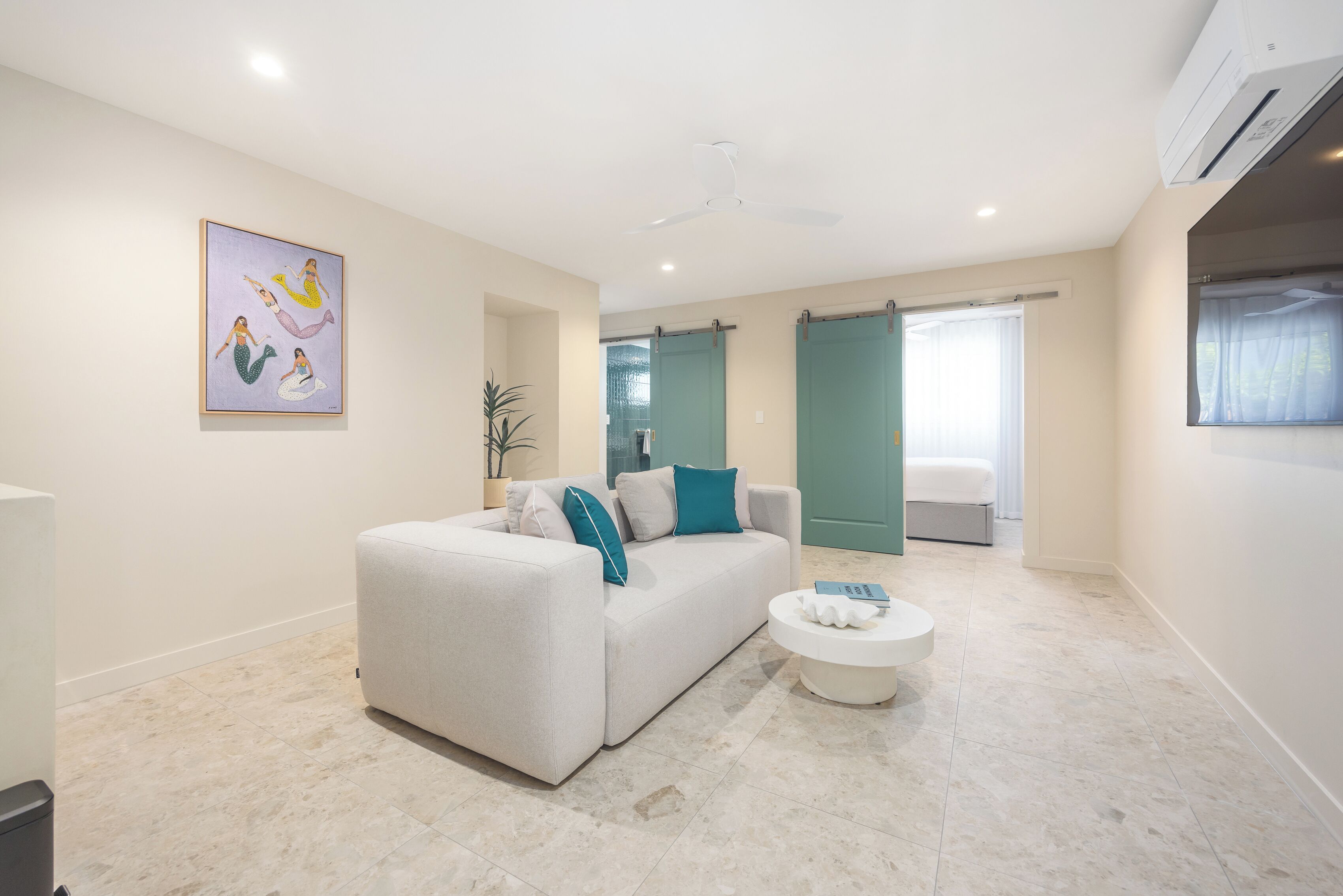 A modern living room with a sofa, a coffee table, and a painting on the wall.