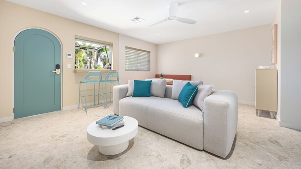 A modern living room with a sofa, two chairs, a coffee table, a ceiling fan, and a door. - The Shores Miami (Miami)