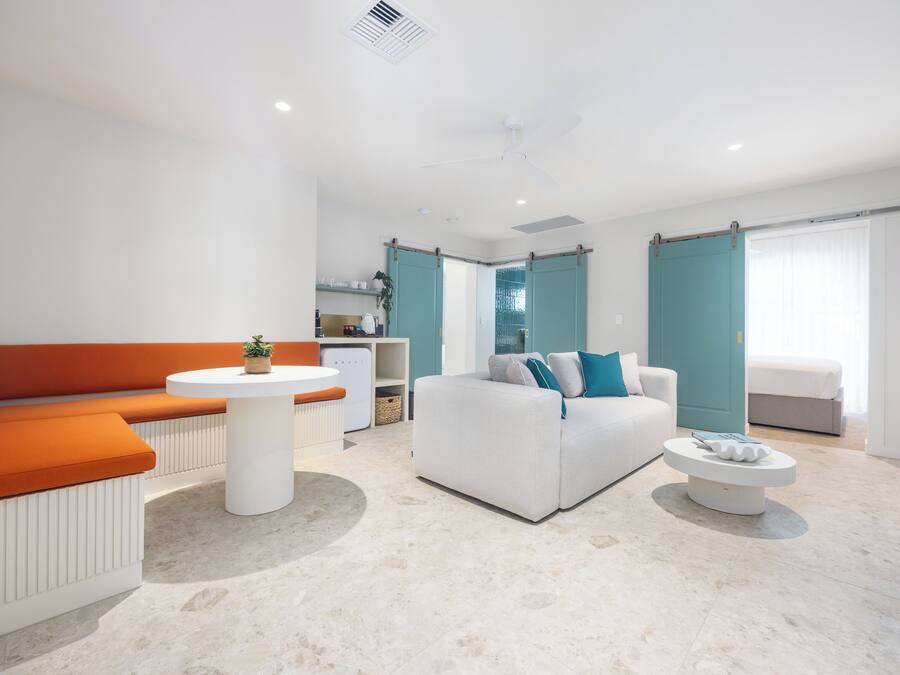 A modern living room with a white sofa, orange bench, and a round coffee table.