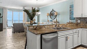 A spacious kitchen with a central island, white cabinetry, and a view of the ocean. - Beachfront Access, 2 Pools, Beach Service w/ Chairs Emerald Isle Resort 1308 (Panama City Beach)