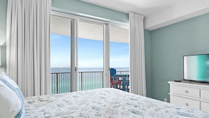 A hotel room with a large bed, a TV, and a balcony with a view of the ocean. - Beachfront Access, 2 Pools, Beach Service w/ Chairs Emerald Isle Resort 1308 (Panama City Beach)