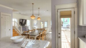 Una cocina amplia con encimera de mármol, mesa de comedor de madera e iluminación colgante.