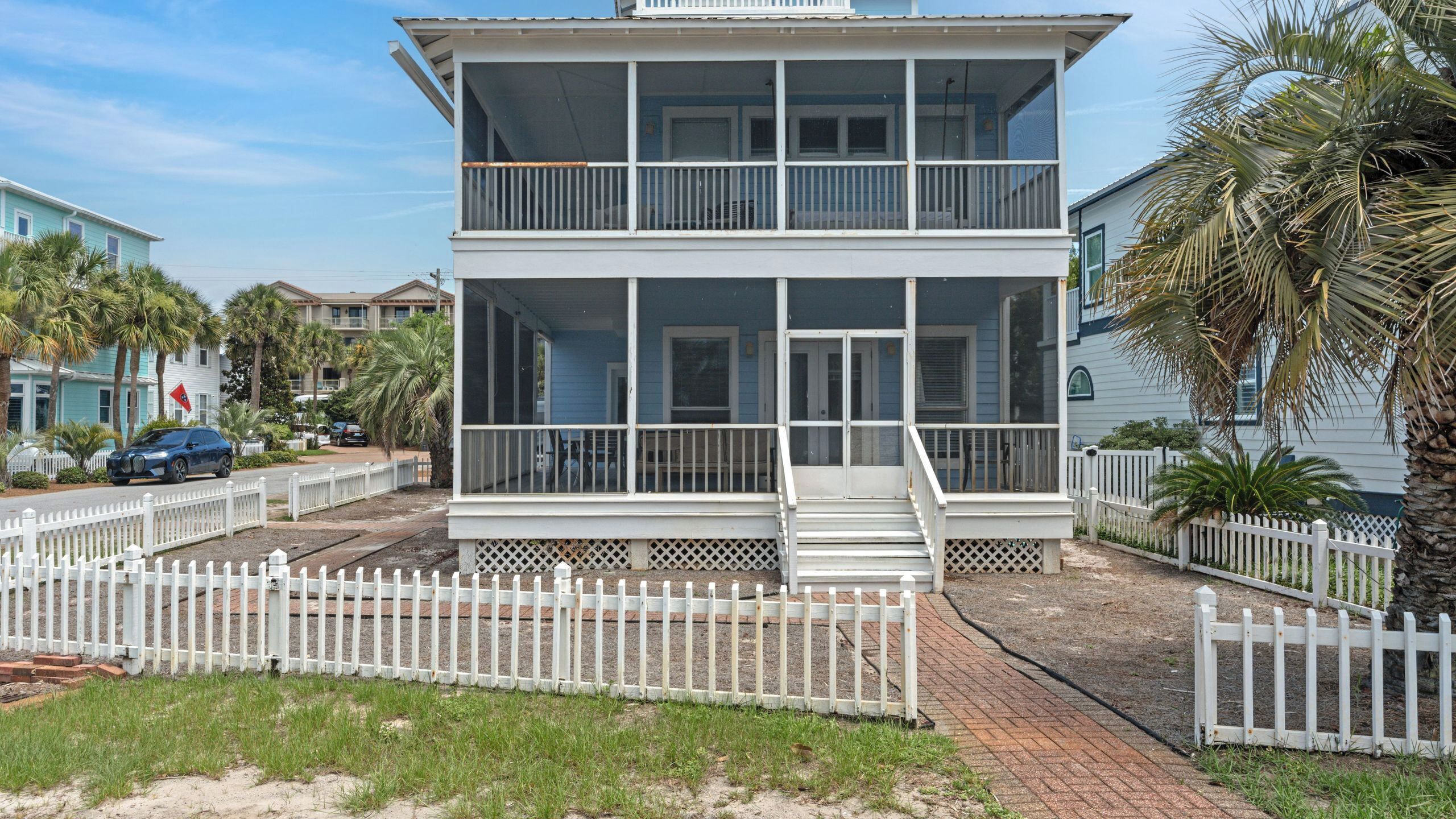 A two-story building with a balcony, a white picket fence, and a clear sky.