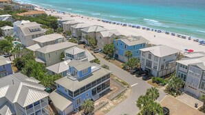 Zona residencial costera con propiedades frente al mar, incluyendo casas con balcones y una playa con sombrillas.