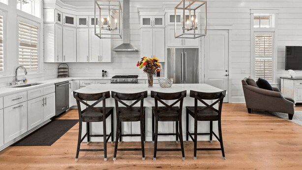 A modern kitchen with white cabinetry, a central island with bar stools, stainless steel appliances, and pendant lighting. - 30A Aqua Vista by Avantstay Golf Cart Included, Pool Acess, Walk to Beach (Santa Rosa Beach)