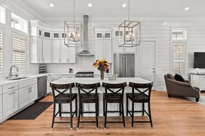 A modern kitchen with white cabinetry, a central island with bar stools, stainless steel appliances, and pendant lighting. - 30A Aqua Vista by Avantstay Golf Cart Included, Pool Acess, Walk to Beach (Santa Rosa Beach)