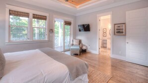 Un dormitorio con una cama grande, un ventilador de techo y vistas al exterior a través de un ventanal corredera.