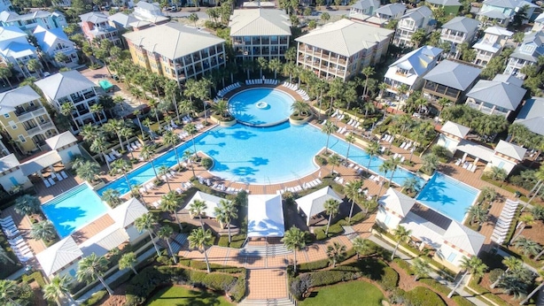 Vista aérea de un complejo turístico con varias piscinas, palmeras y edificios del resort.