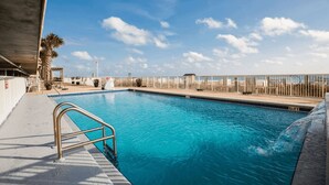 A swimming pool with a metal ladder, lounge chairs, and a palm tree.