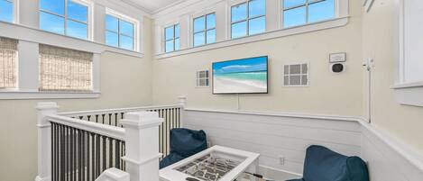 A room with a high ceiling, large windows, a foosball table, and a view of the beach.