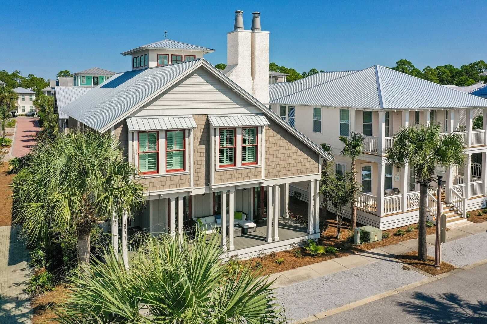 Una casa costera con porche envolvente, varias chimeneas y un balcón.