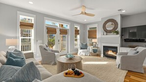A modern living room with a fireplace, comfortable seating, and large windows.