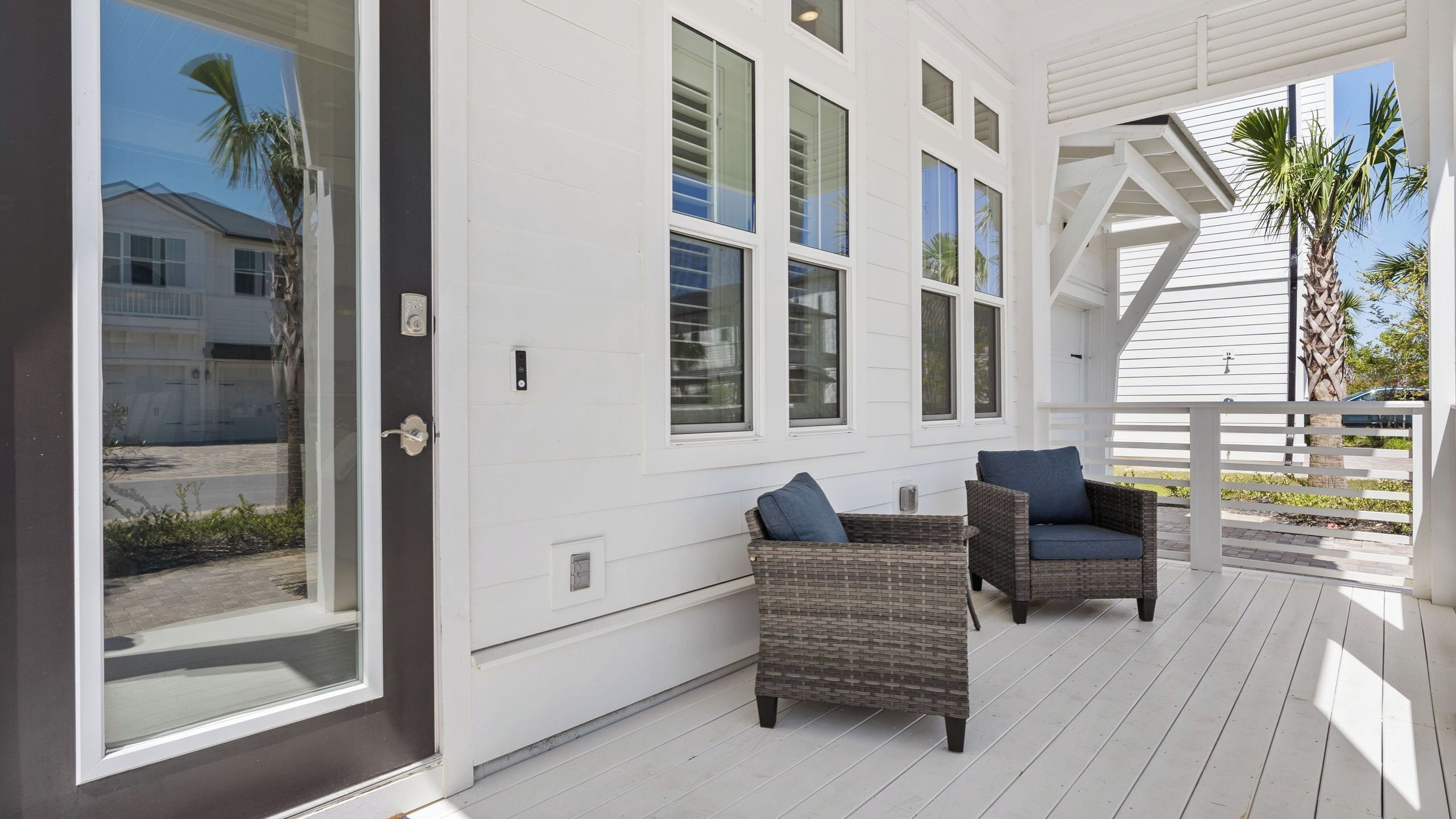 A covered porch with wicker furniture, large windows, and a view of the street.
