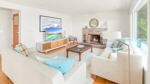 Ein modernes Wohnzimmer mit Kamin, Fernseher und einer Couch.