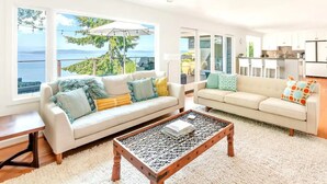 Ein modernes Wohnzimmer mit einem weißen Sofa, einem Couchtisch und Meerblick.