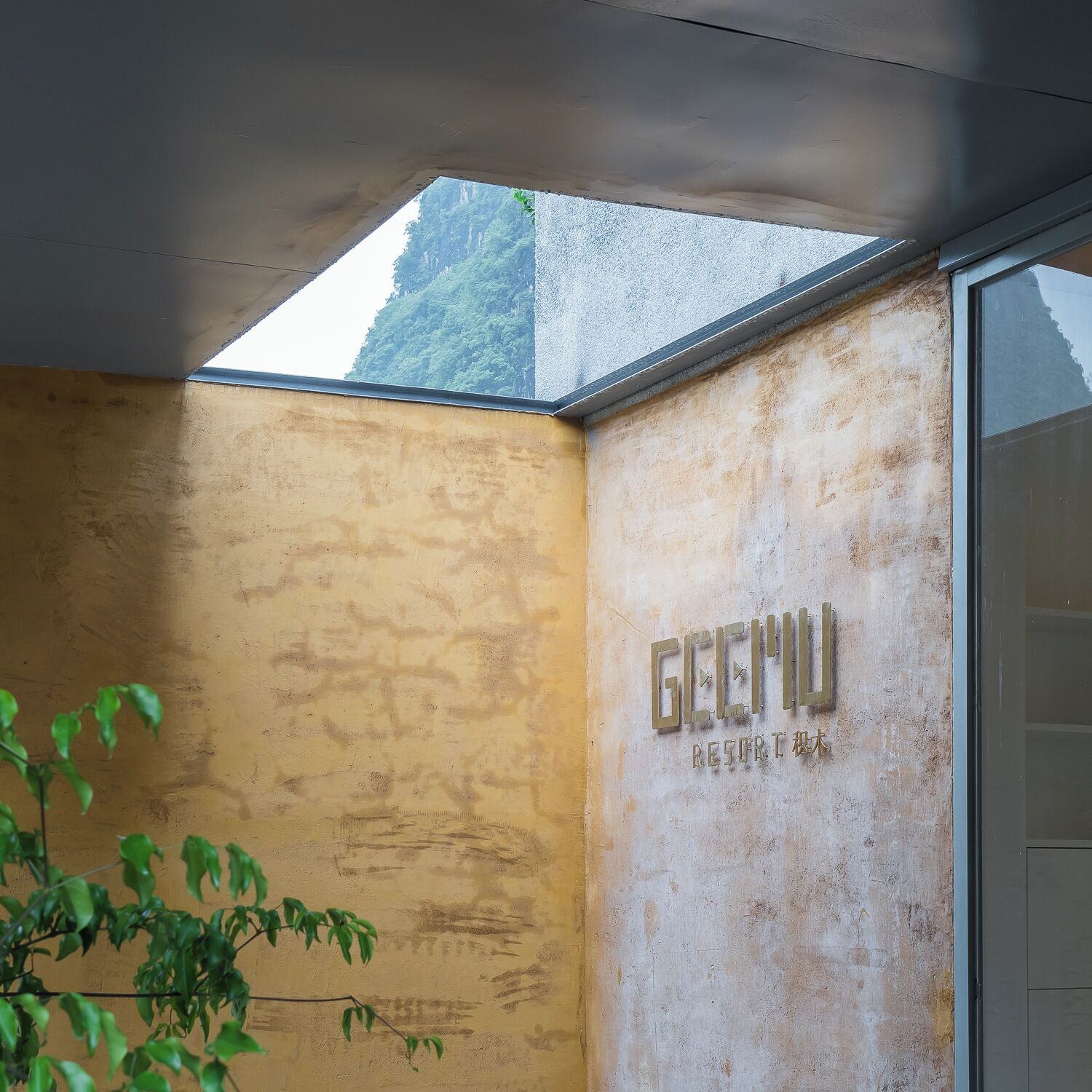 A corner of a room with a textured wall and a window. The wall has a sign that reads "GECHU RESORT".