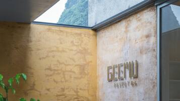 A corner of a room with a textured wall and a window. The wall has a sign that reads "GECHU RESORT".