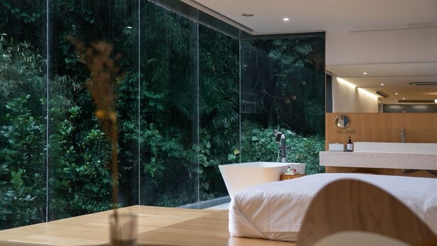 A modern bedroom with a large window, a bathtub, and a view of mountains. - Yangshuo Geemu Building House (Guilin)