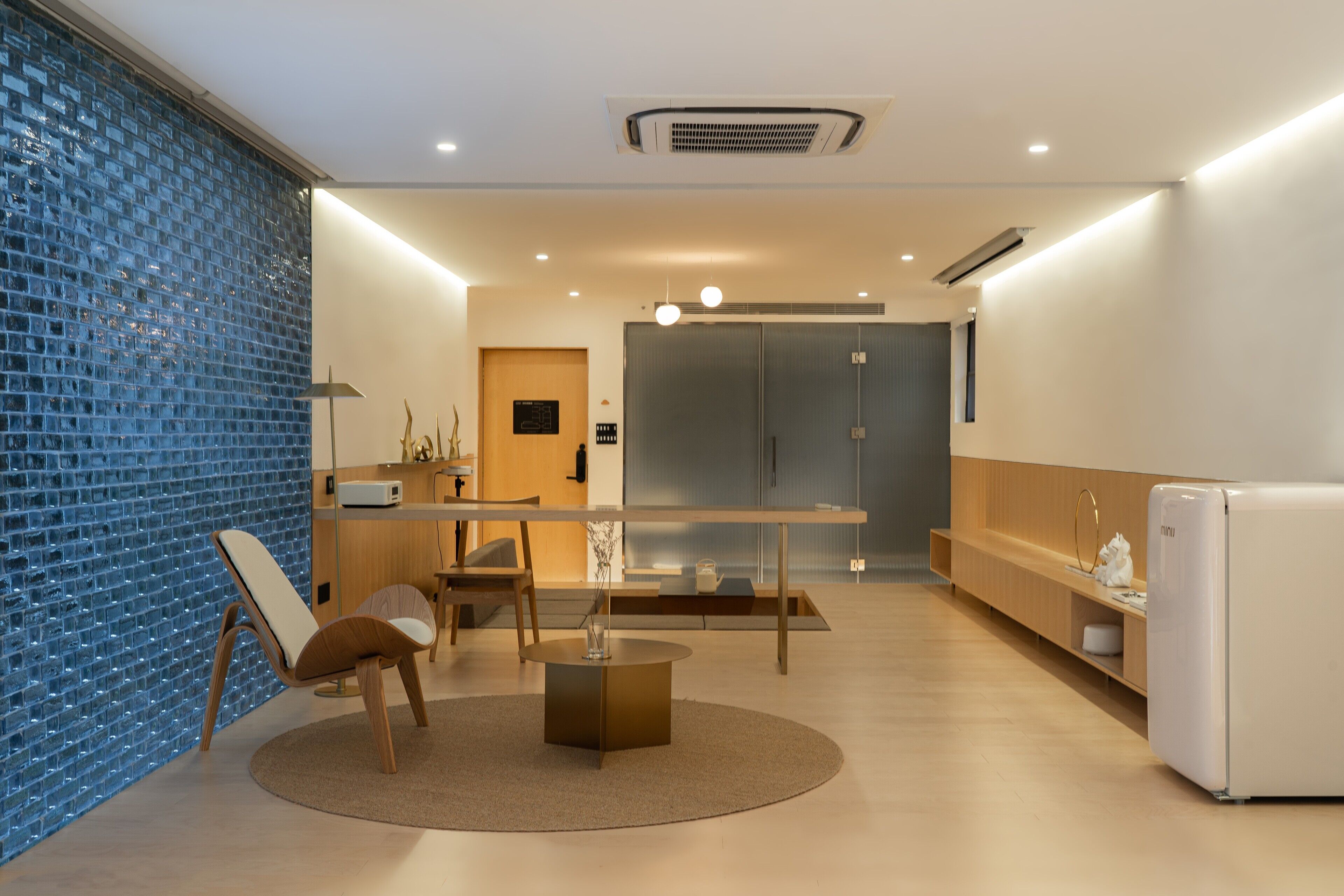 A modern kitchen with a dining area, featuring a round table, chairs, and a refrigerator.