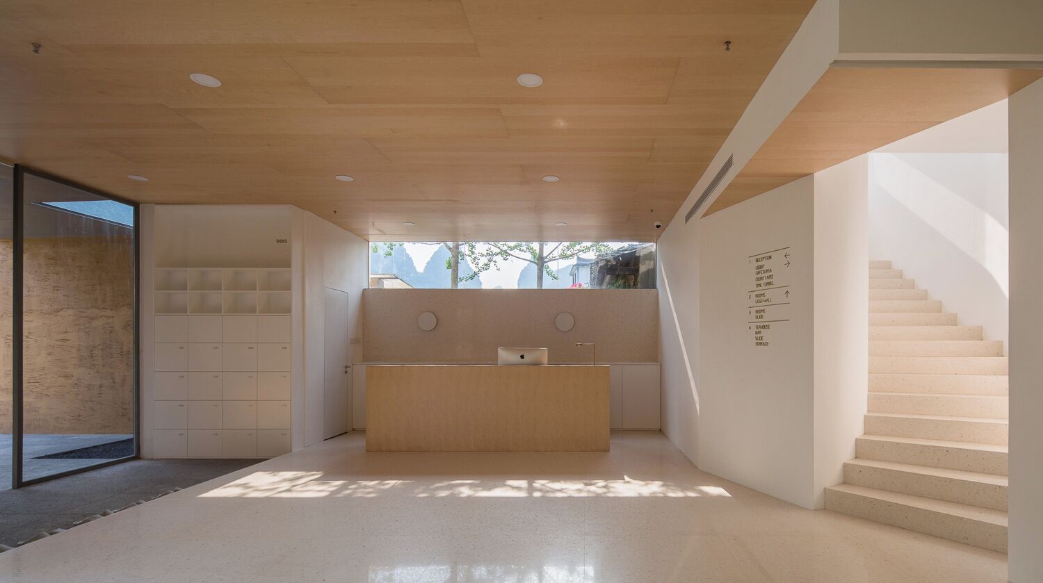 Een modern interieur met een receptiebalie, een trap en uitzicht op het buitengebied.