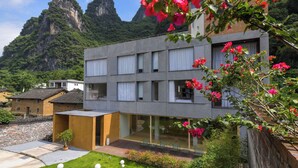 A modern building with a flat roof, large windows, and a balcony with outdoor seating. - Yangshuo Geemu Building House (Guilin)