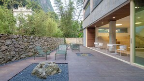 A modern building with a stone wall and outdoor seating area with chairs and tables. - Yangshuo Geemu Building House (Guilin)
