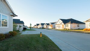 A row of single-family homes with a well-maintained lawn and a fire hydrant in the foreground. - The Rehoboth- Iowa -Entire Home, 4BR- Deluxe & Elegant, Great Location near I-35 (Ankeny)