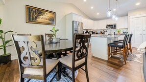 A modern kitchen with white cabinets, stainless steel appliances, and a central island with bar stools. - The Rehoboth- Iowa -Entire Home, 4BR- Deluxe & Elegant, Great Location near I-35 (Ankeny)