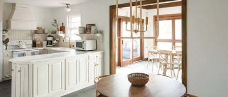 A kitchen with white cabinetry, a central island, and a dining area with a round table and chairs.
