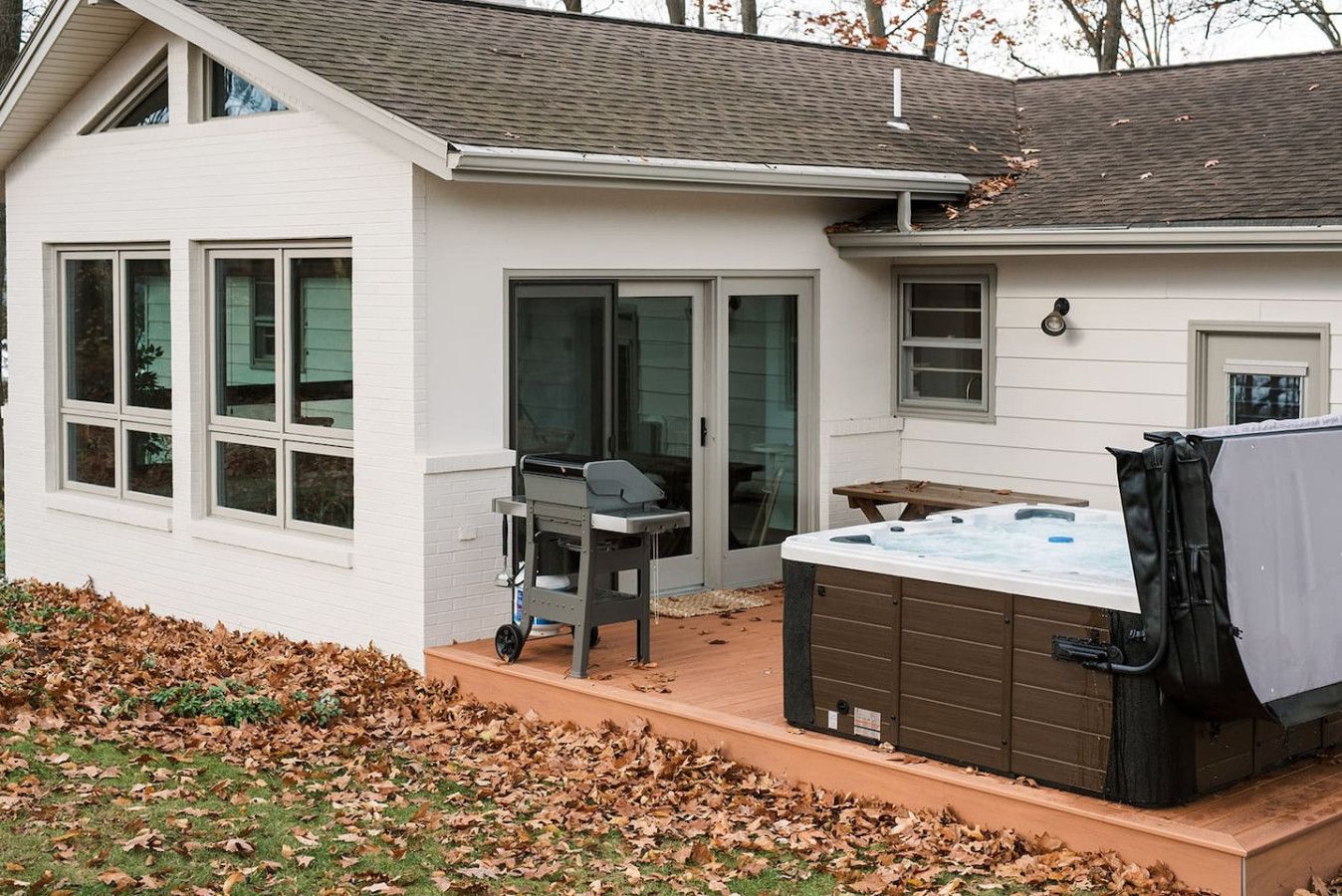 Ein Haus mit Terrasse, Whirlpool und Grill.