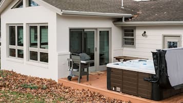 Ein Haus mit Terrasse, Whirlpool und Grill.