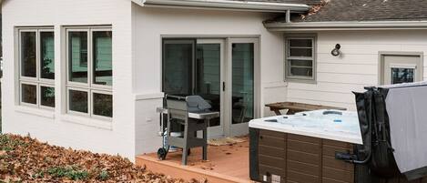 A house with a patio, a hot tub, and a grill.