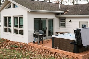 Een huis met een terras, een jacuzzi en een barbecue.