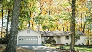 Une maison de plain-pied avec un garage, entourée d’arbres aux feuilles d’automne.