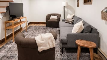 A living room with a sofa, armchair, TV on a stand, and a floor lamp.