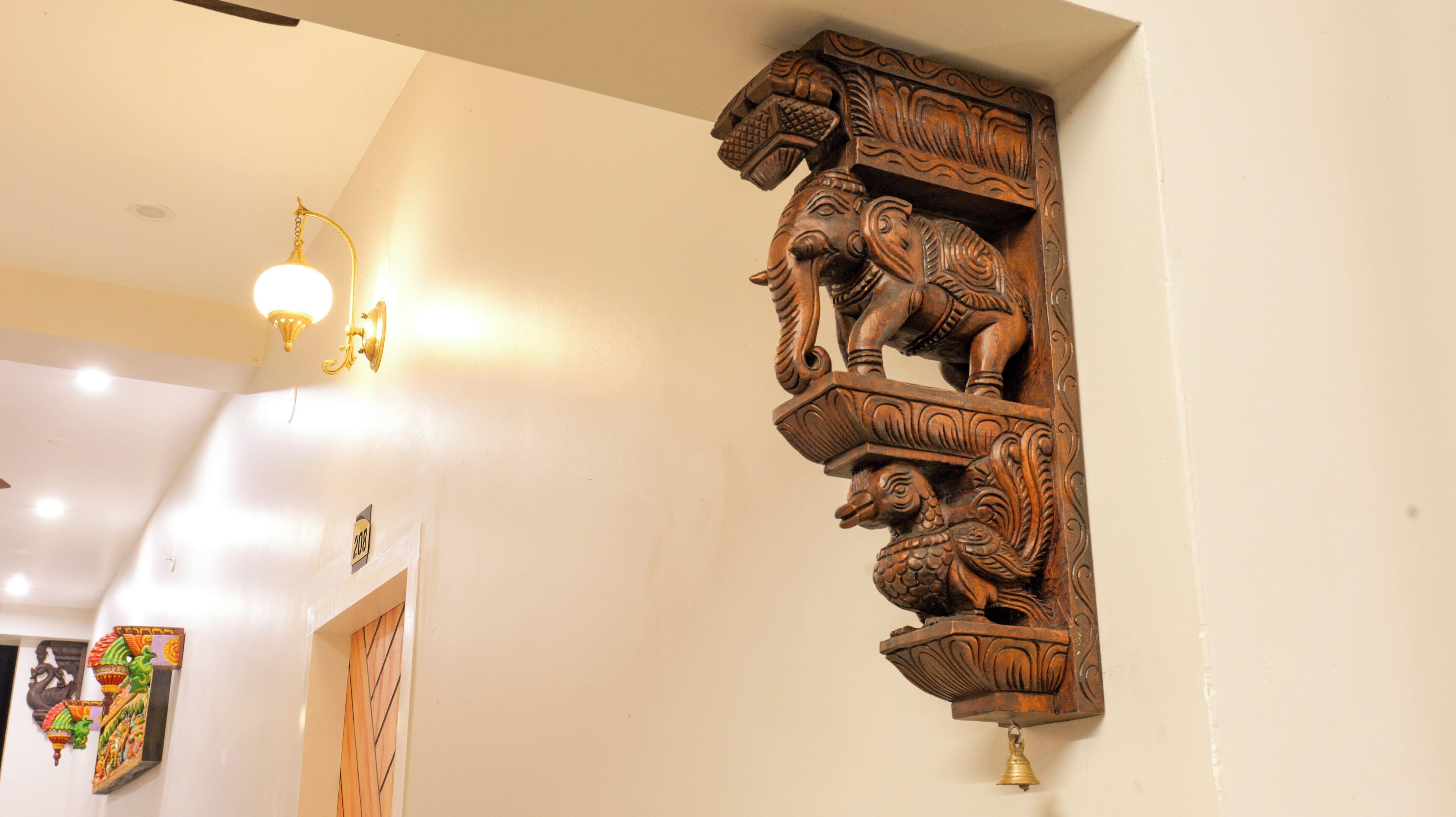 Een houten wandsculptuur met ingewikkelde gravures, een lamp en een deur met decoratief paneel.