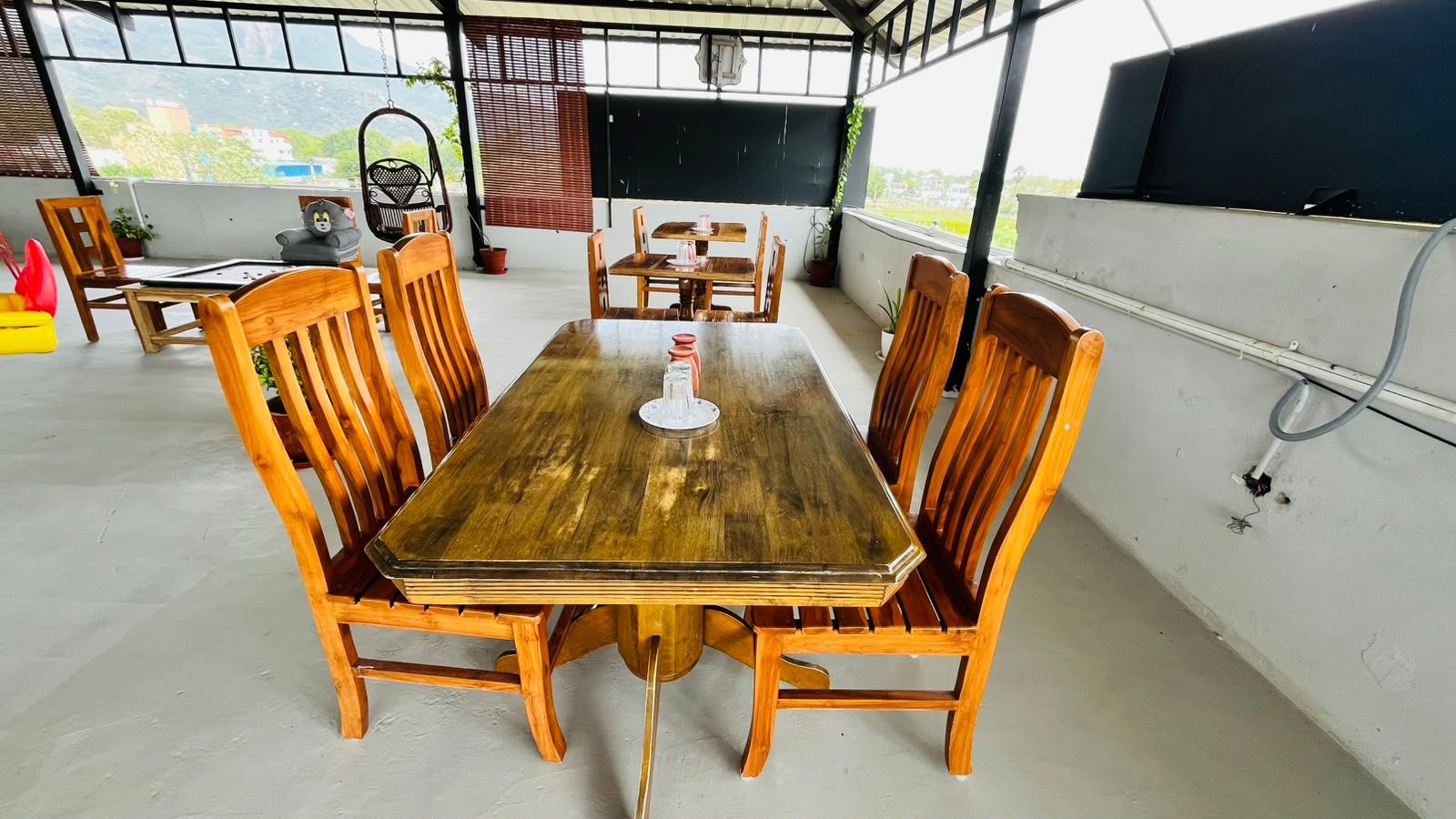 Een houten eettafel met zes stoelen, een hangstoel en uitzicht op de omgeving.
