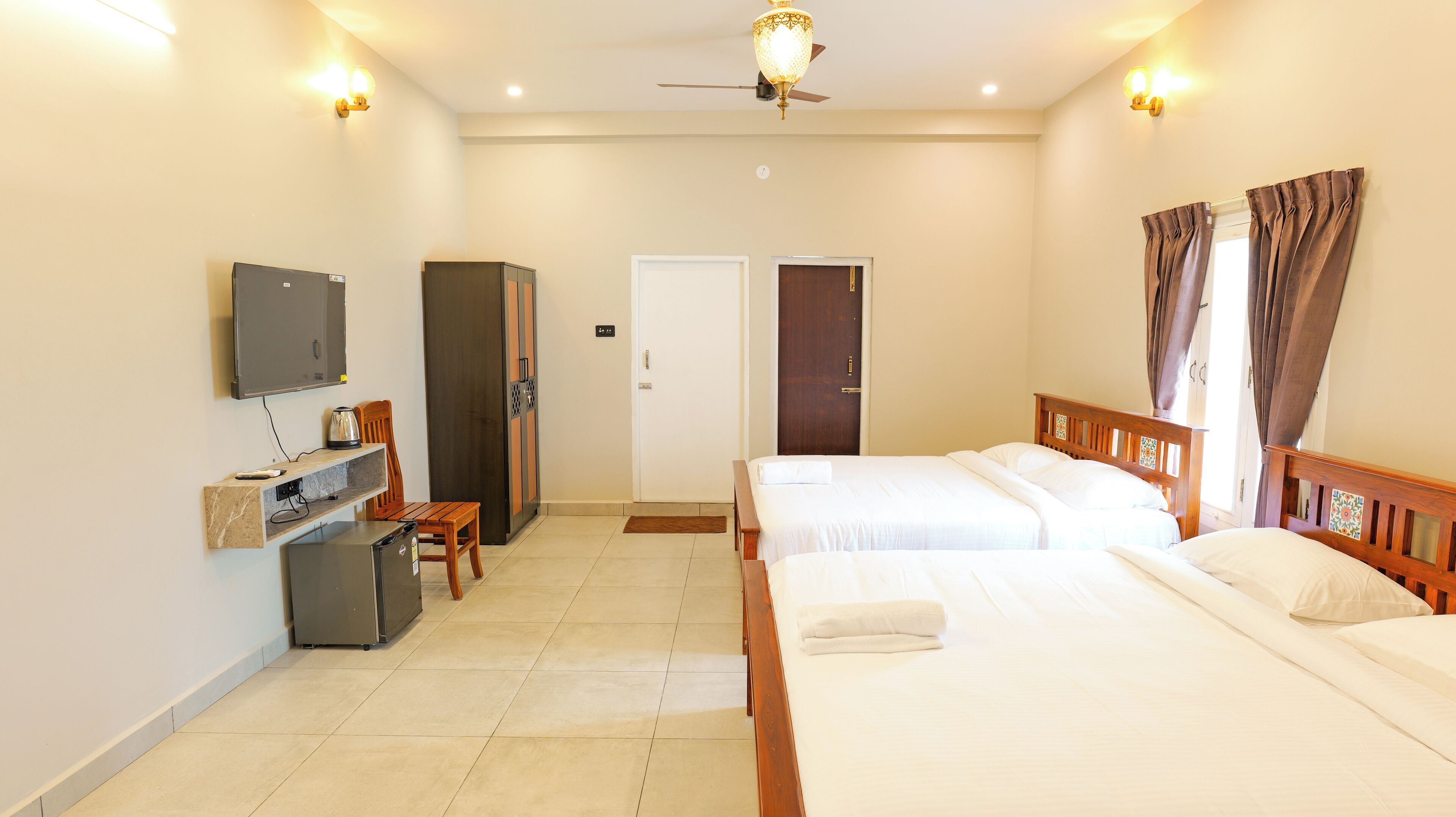 Habitación de hotel con dos camas, un escritorio con computadora, televisión y armario.