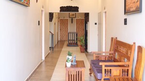Una hall d'albergo con una ventola a soffitto, un divano, un tavolino da caffè e un elemento decorativo a parete.