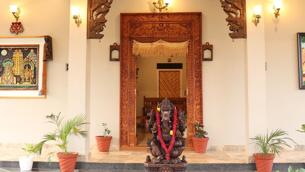 Un'imponente ingresso con un arco in legno decorativo, una statua su un piedistallo e un pavimento a motivi.