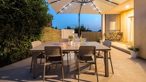 Un patio exterior con mesa y sillas, una sombrilla y vista al mar.